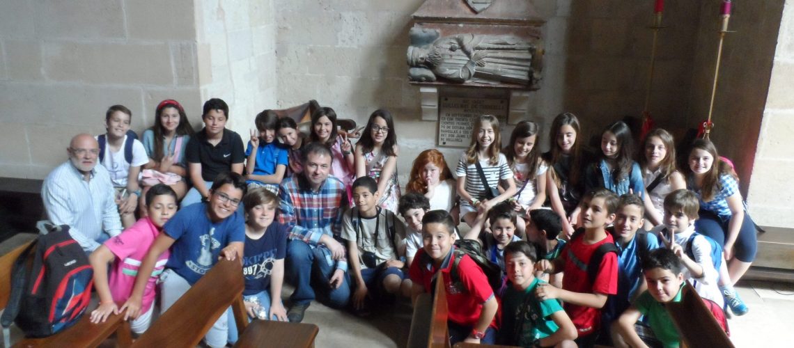 El grup d'alumnes de 5è de primària davant el sepulcre de Guillem de Torrella a l'església de Santa Margalida (Palma) amb el seu tutor, Jaume Oliver, i Ramon Rotger, director d'esdeveniments del Centre d'Història i Cultura Militar de les Balears.